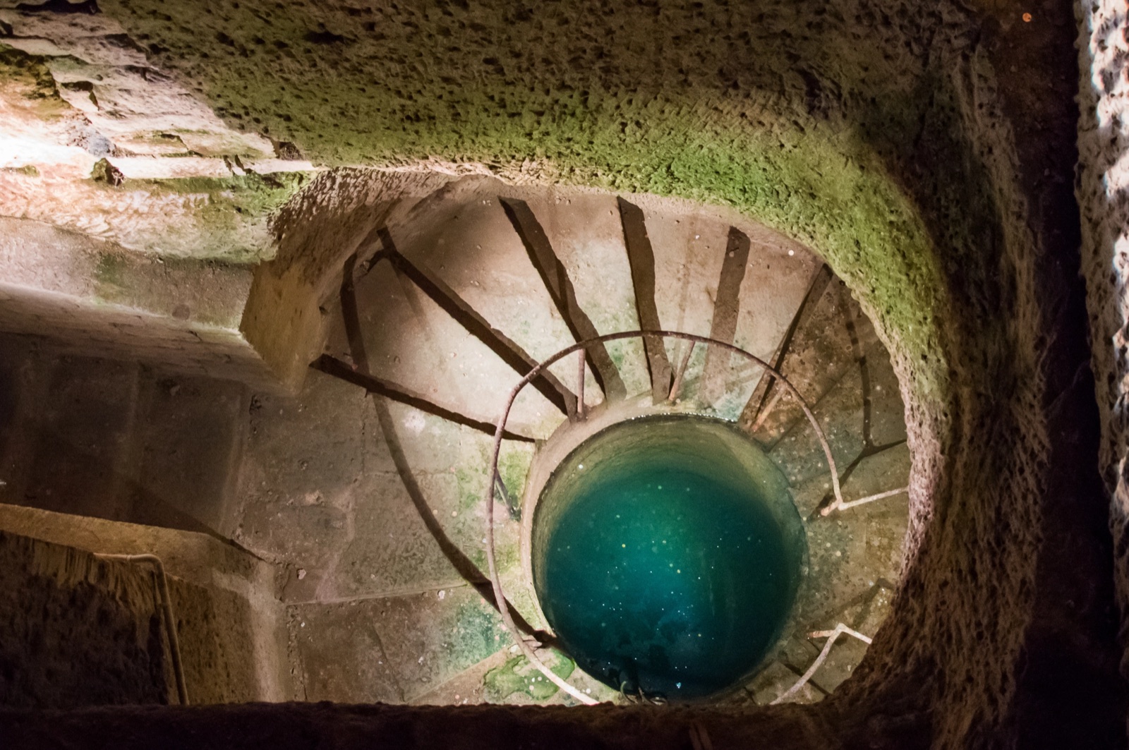 Spiral stone staircase descending into the Paris Catacombs