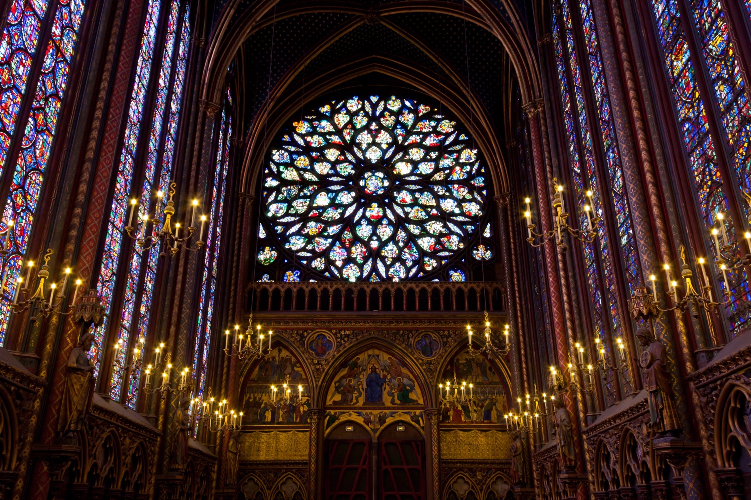 The rose window of Sainte-Chapelle glowing above candlelit chandeliers, Paris